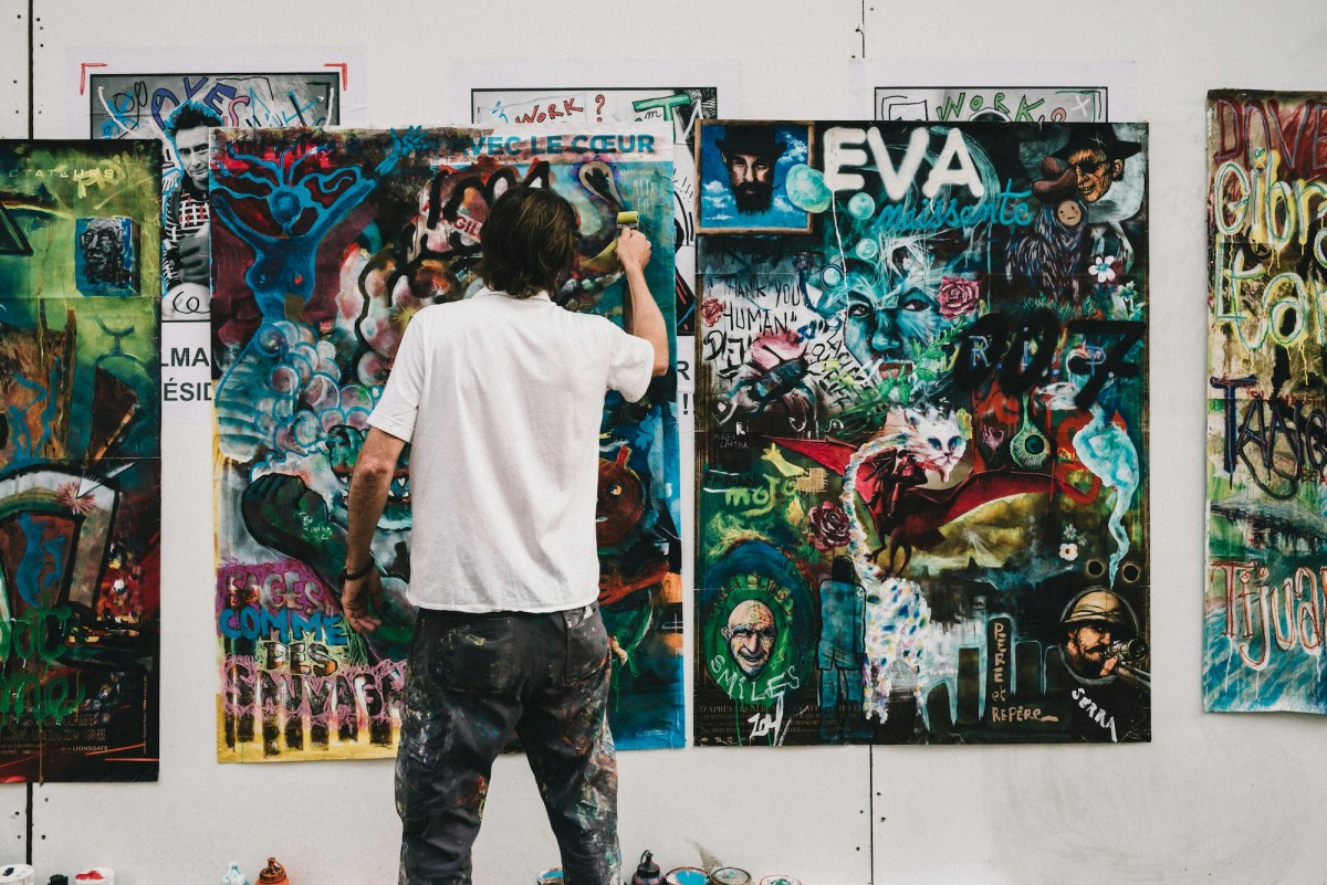 rear view of man working on a painting in an artist studio. Exhibition.