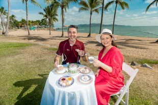 Happy image of woman in red dress and man in t-shirt having a tea party in tropical location. Wedgwood