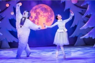 A ballerina is dancing with a snowman. There are trees covered with sow snow around them and a moon behind them.