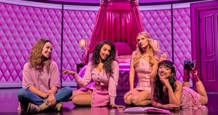 Four young women in a pink bedroom. They too are dressed in pink in a production of 'Mean Girls.'