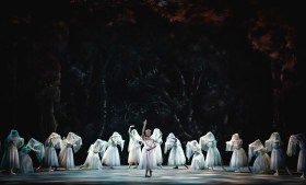 Ballerinas in white tutus, with white veils over their heads, with a single dancer in the middle.