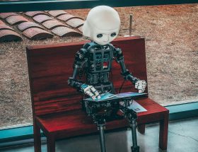 A robot child sits on a bench looking at a screen on its lap. AI